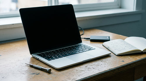 Ordinateur portable à l'écran noir posé sur un bureau de dépannage
